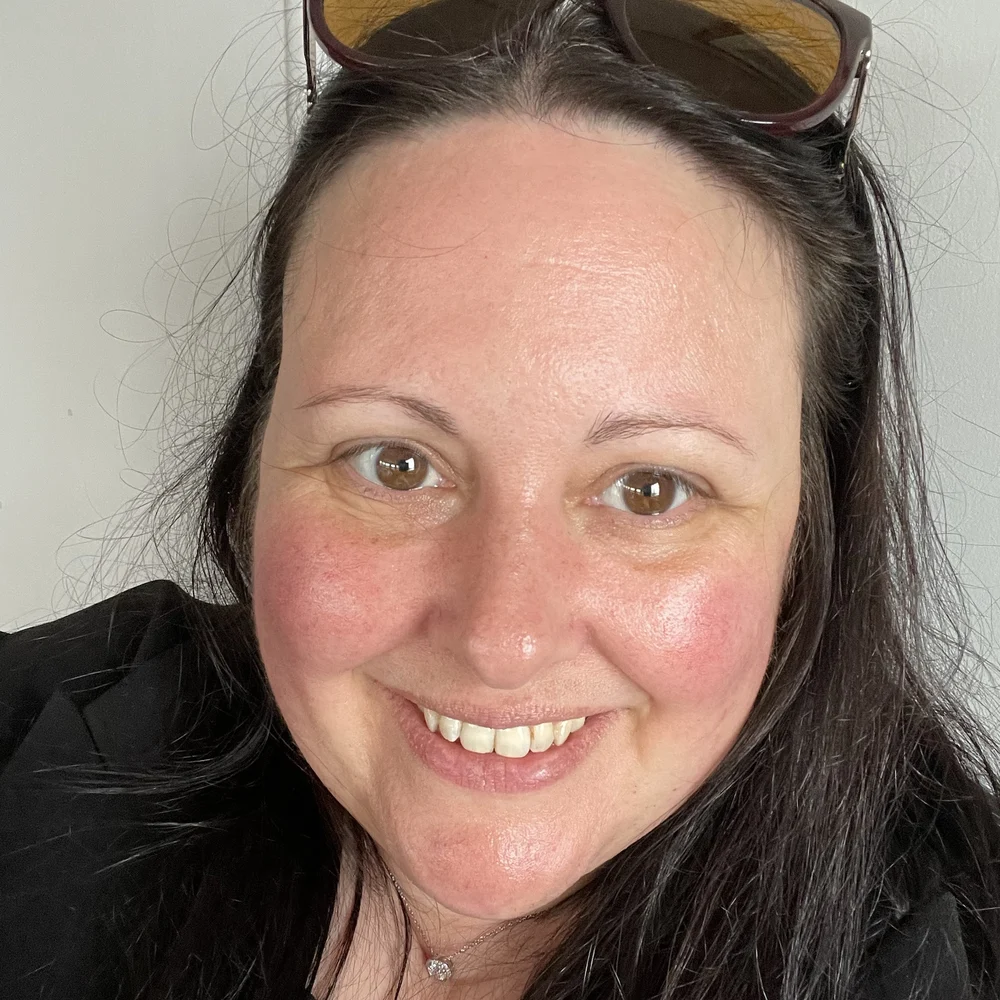 Helena, the voice and lyricist behind LENA, smiling, with sunglasses pushed up in her dark hair